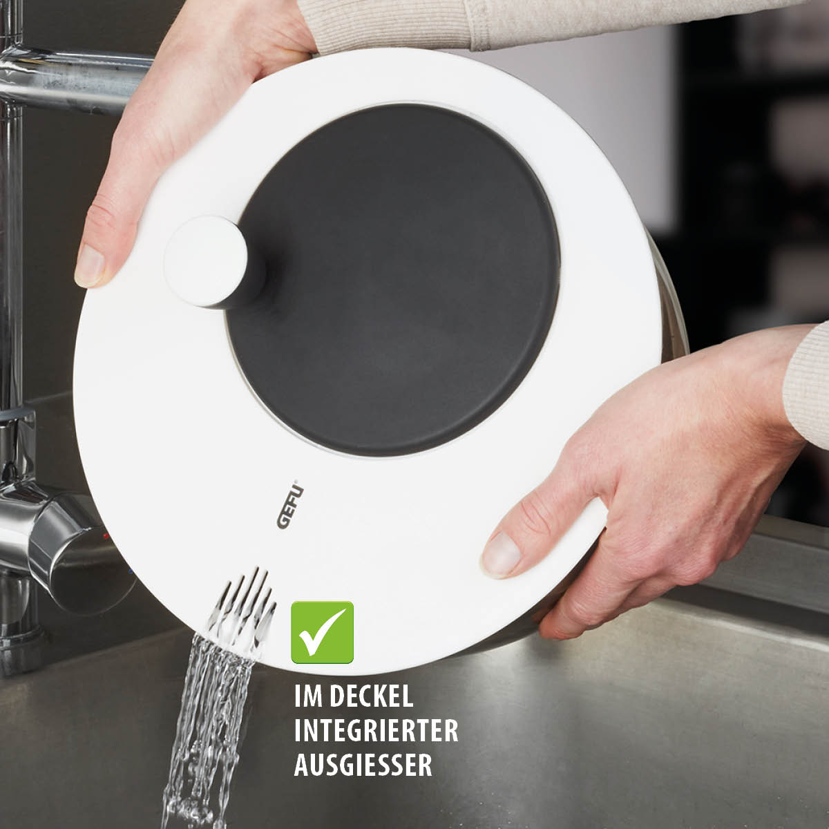 Gefu Kochtopfdeckel mit integriertem Ausgießer Ein Gefu Kochtopfdeckel mit integriertem Ausgießer, durch den Wasser in eine Spüle abgelassen wird.