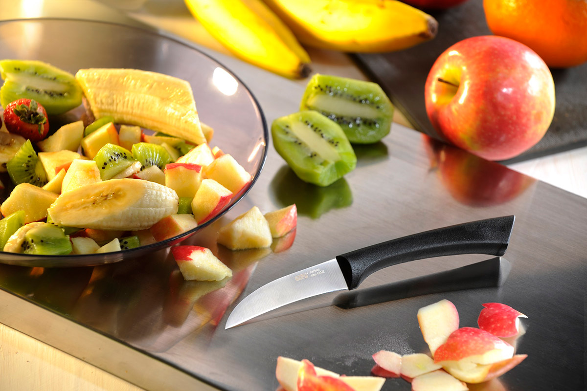 Frischer Obstsalat mit Kiwis, Bananen und Äpfeln auf Schneidebrett mit Messer Geschnittene Kiwis, Bananen und Äpfel für einen Obstsalat auf einem Schneidebrett mit einem Küchenmesser