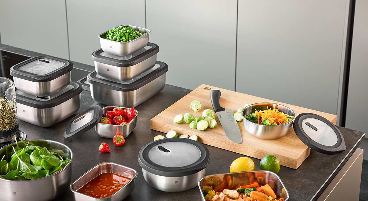 Edelstahl-Aufbewahrungsbehälter und frisches Gemüse auf Küchenarbeitsplatte Mehrere stapelbare Edelstahl-Aufbewahrungsbehälter und frisches Gemüse, darunter Erbsen und Rosenkohl, auf einer Küchenarbeitsplatte