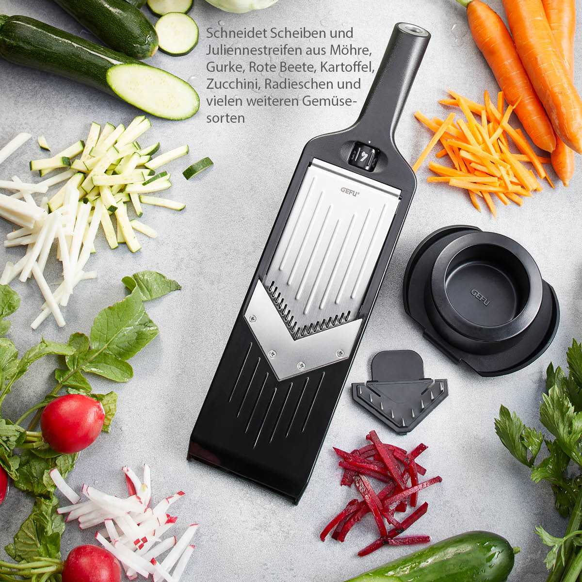 Mandoline-Gemüseschneider für Scheiben und Streifen Mandoline-Gemüseschneider mit frischem, in Scheiben und Streifen geschnittenem Gemüse auf einem Tisch, darunter Möhren, Gurken und Radieschen.
