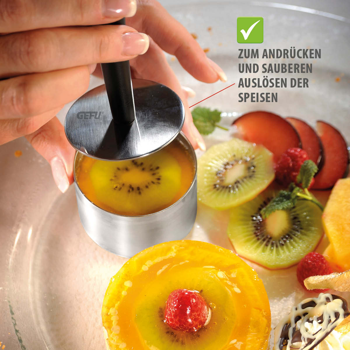 Hände nutzen ein Küchengerät zum sauberen Auslösen von Speisen, umgeben von Früchten wie Kiwi und Himbeeren.