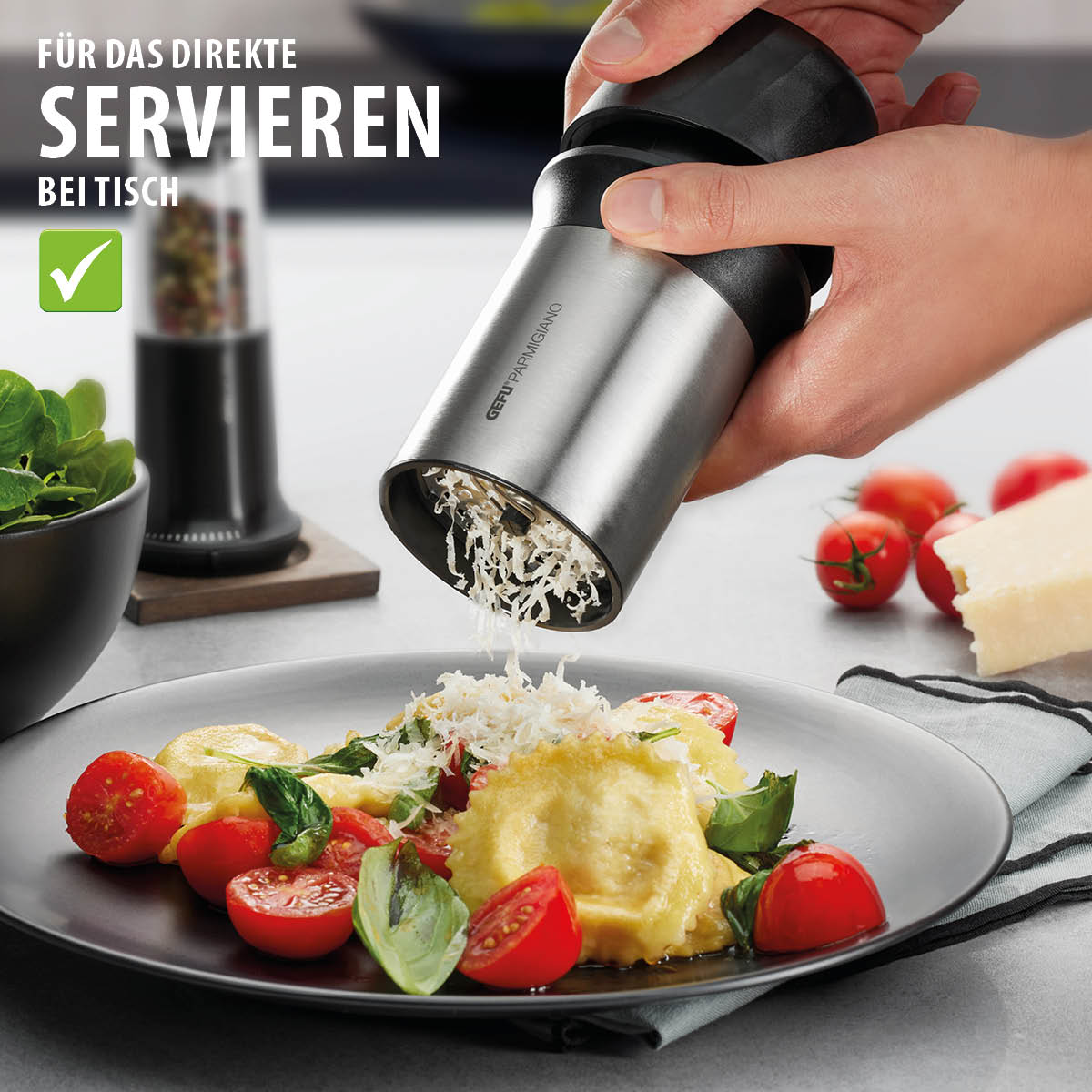 Hand verwendet Käsereibe über einem Teller mit gefüllten Teigtaschen und Tomaten