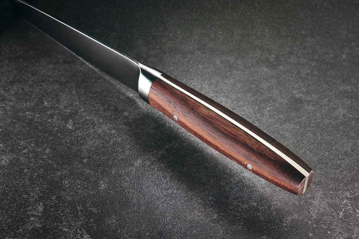 Hochwertiges Küchenmesser mit Holzgriff Detailansicht eines Küchenmessers mit elegantem Holzgriff auf dunkler Oberfläche.