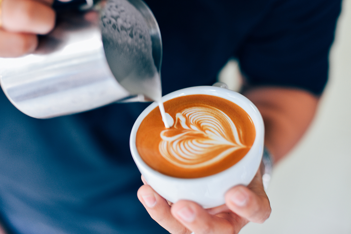 Nahaufnahme von Latte Art mit Herzmuster auf einem frisch gebrühten Kaffee, der in einer weißen Tasse serviert wird