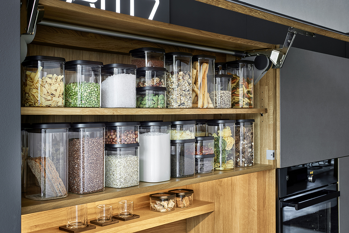 Organisierte Vorratsdosen in einem Küchenregal Küchenregal mit verschiedenen Vorratsdosen gefüllt mit Pasta, Hülsenfrüchten, Nüssen und anderen Zutaten.