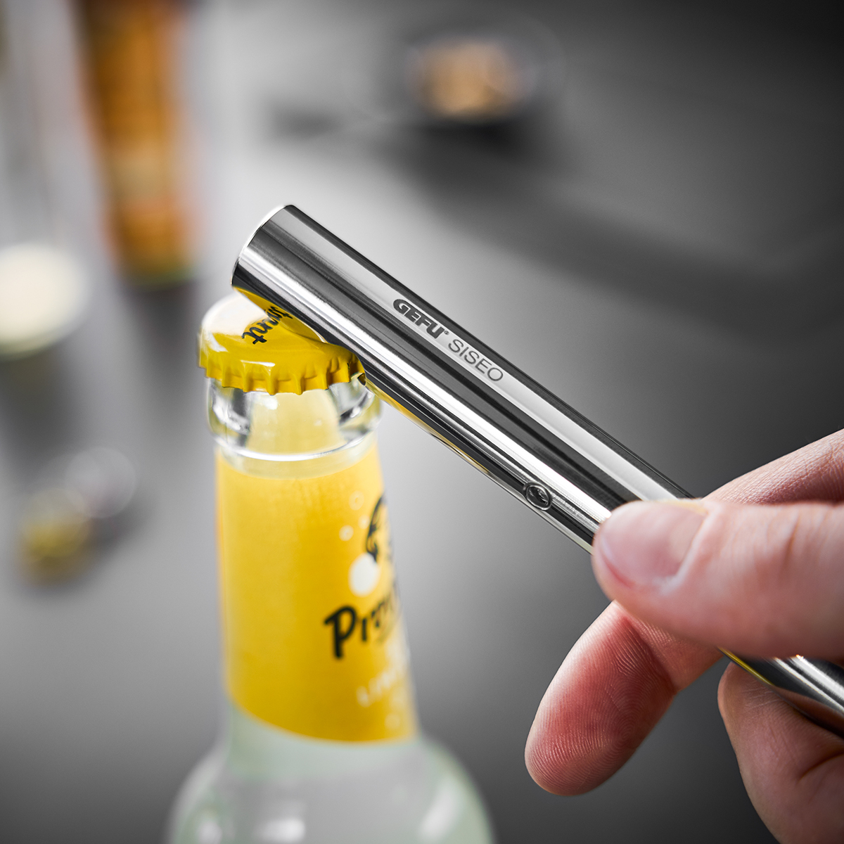 Nahaufnahme eines Flaschenöffners, der eine Flasche mit gelbem Kronkorken öffnet