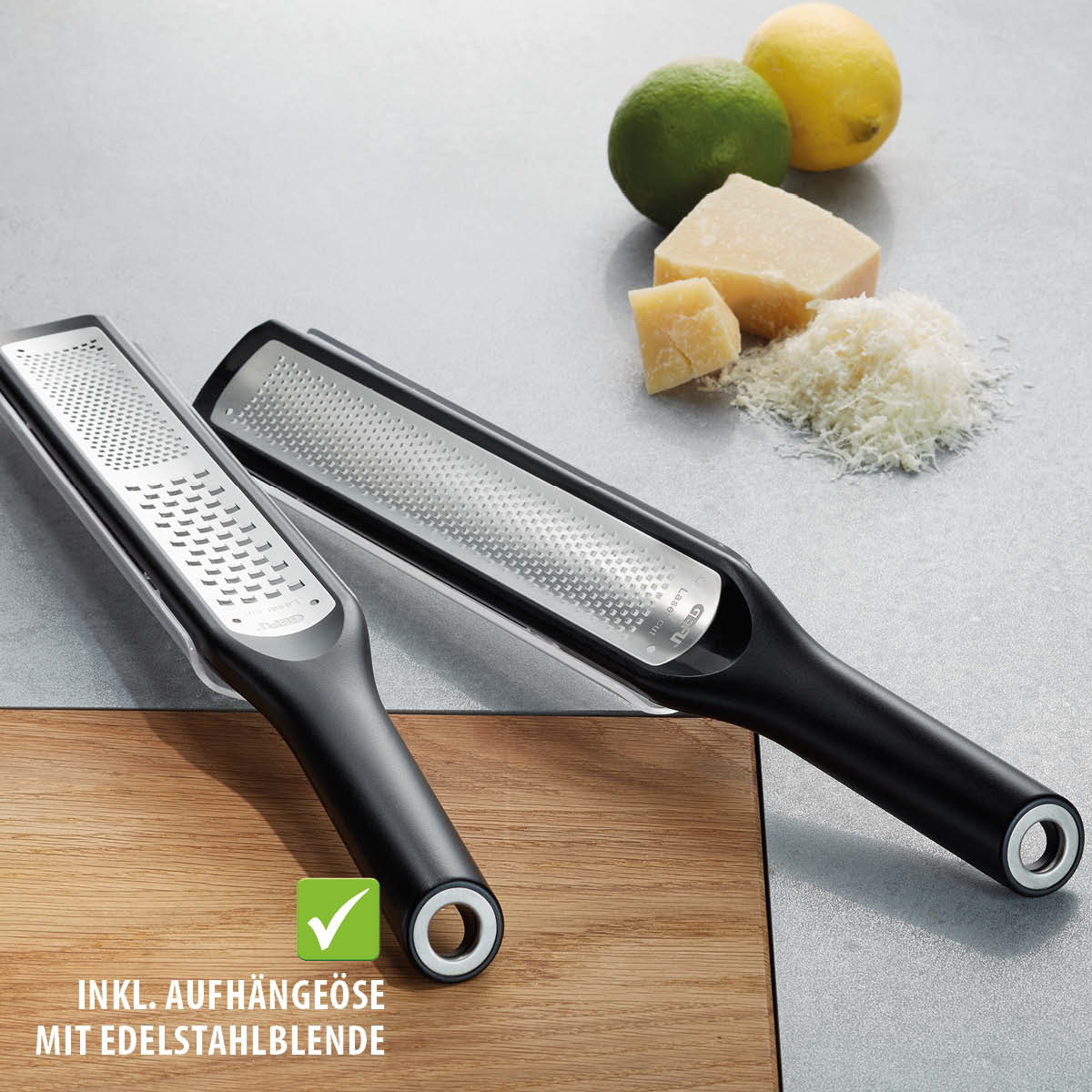 Premium Edelstahlreibe mit Aufhängeöse für Käse und Zitrusfrüchte Edelstahlreibe mit schwarzem Griff, ideal für das Reiben von Käse und Zitrusfrüchten, inklusive Aufhängeöse, auf einer Küchenoberfläche mit Parmesan und Zitronen im Hintergrund platziert