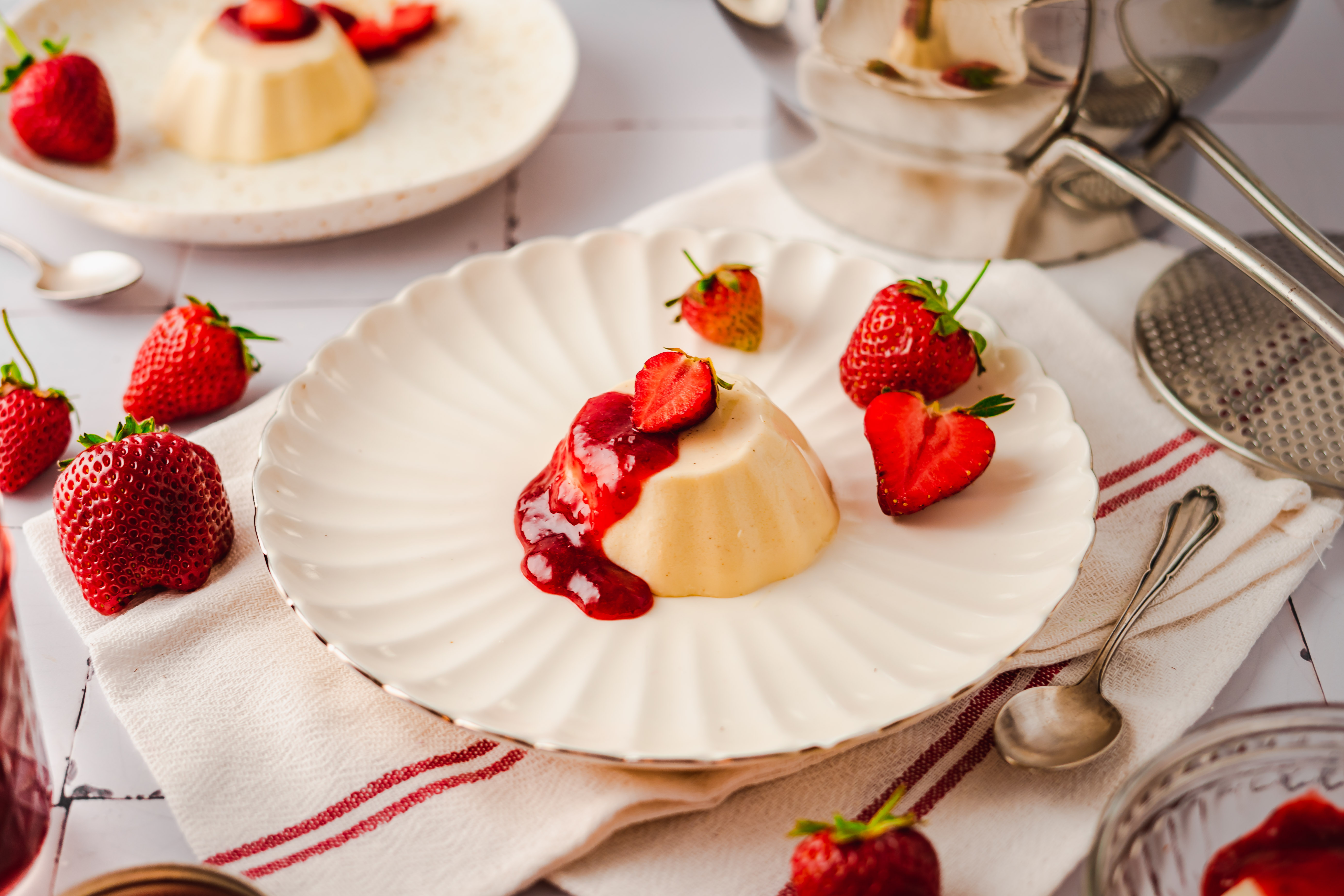 Vegetarische Panna Cotta mit Erdbeermarmelade  Ein Teller mit Panna Cotta und Erdbeersauce, umgeben von frischen Erdbeeren
