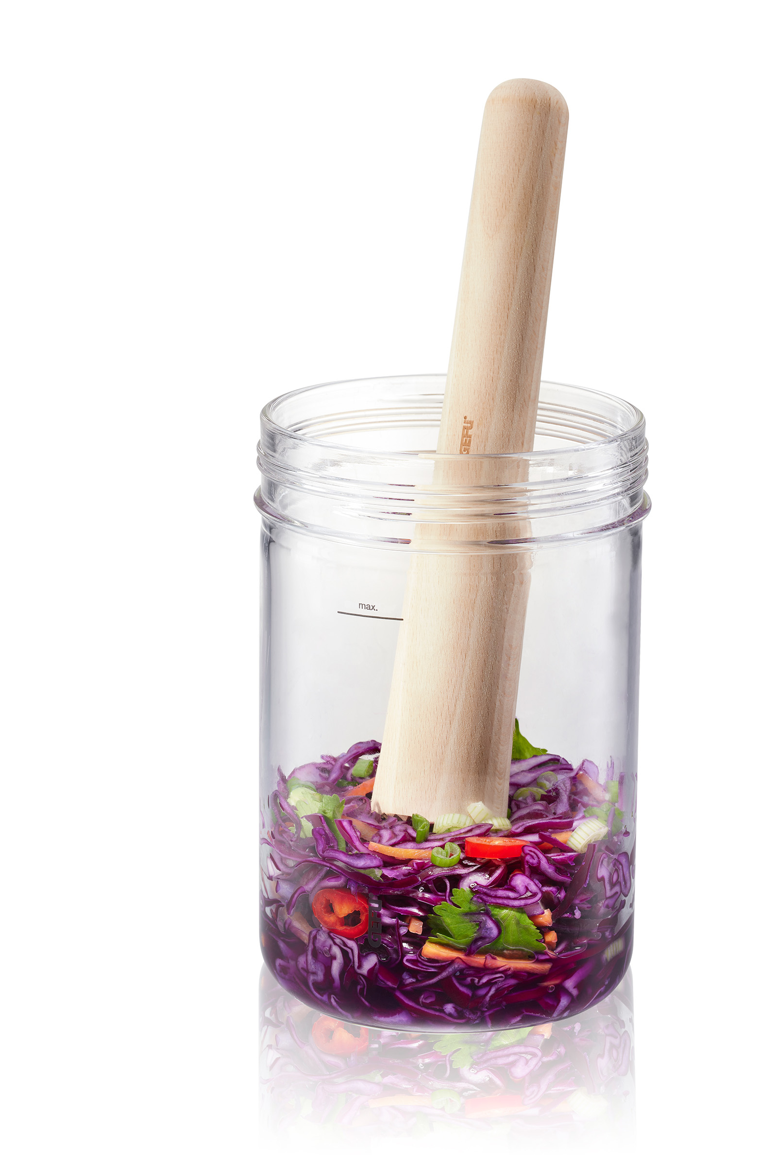 Fermentationsglas mit Krautstampfer aus Holz Ein Glas mit Deckel, gefüllt mit gehobeltem Rotkohl und anderen Gemüsen, mit einem hölzernen Stampfer darin.