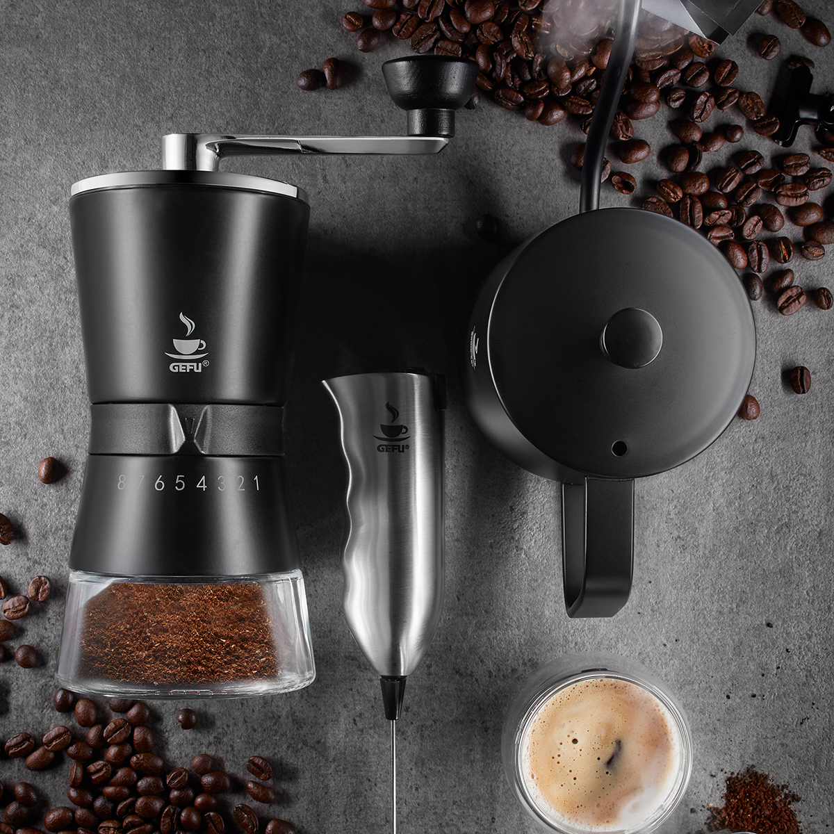Kaffeezubehör-Set mit Handmühle, Milchaufschäumer, Kaffeekanne und Kaffeebohnen Flachbildansicht von einem Kaffeezubehör-Set mit Handmühle, Milchaufschäumer, Kaffeekanne und verstreuten Kaffeebohnen auf grauer Oberfläche