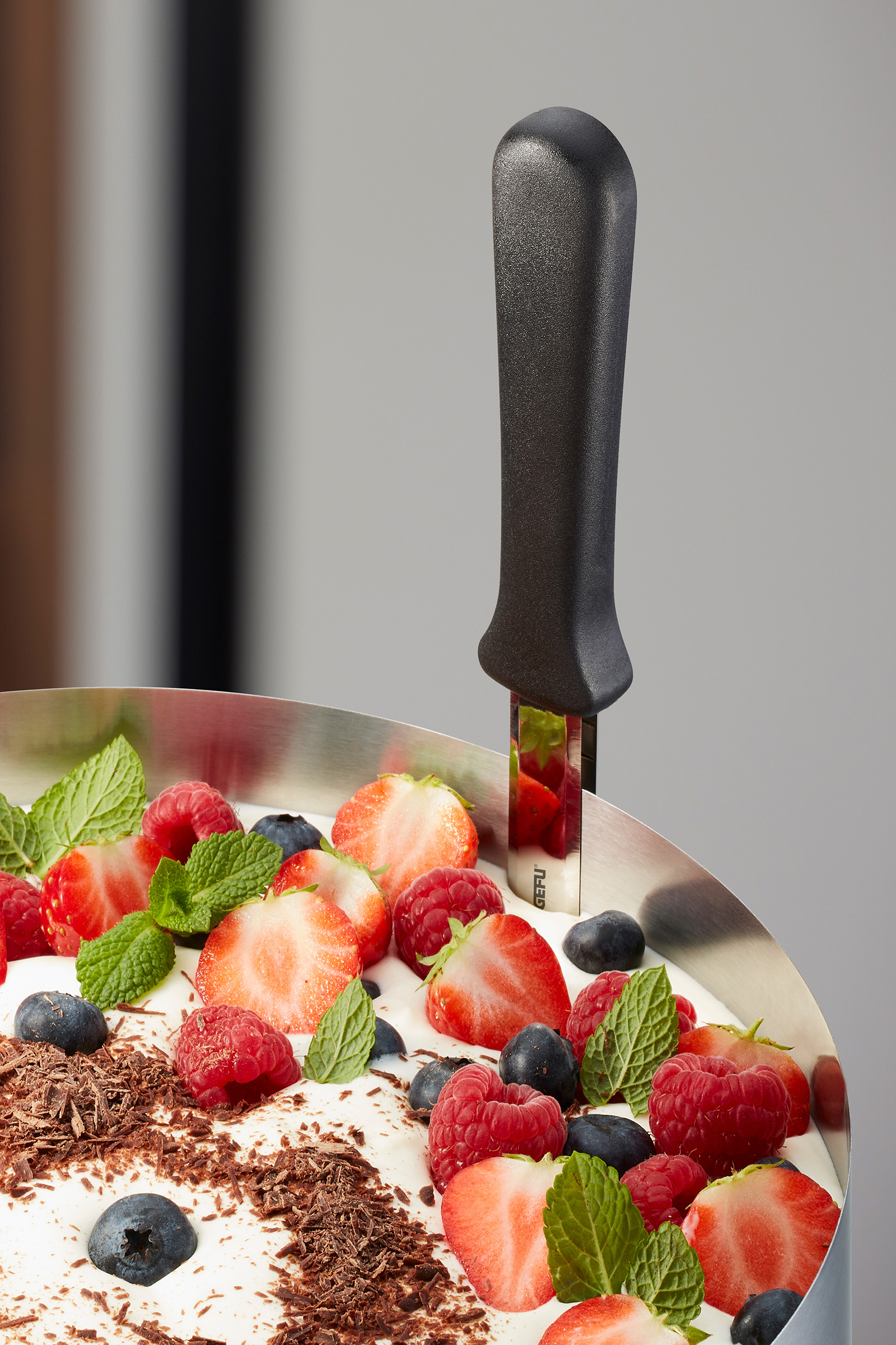 Kuchenring mit frischen Beeren und Minzblättern dekoriert Ein Dessert im Kuchenring, garniert mit Erdbeeren, Himbeeren, Blaubeeren, Minzblättern und Schokoladenraspeln
