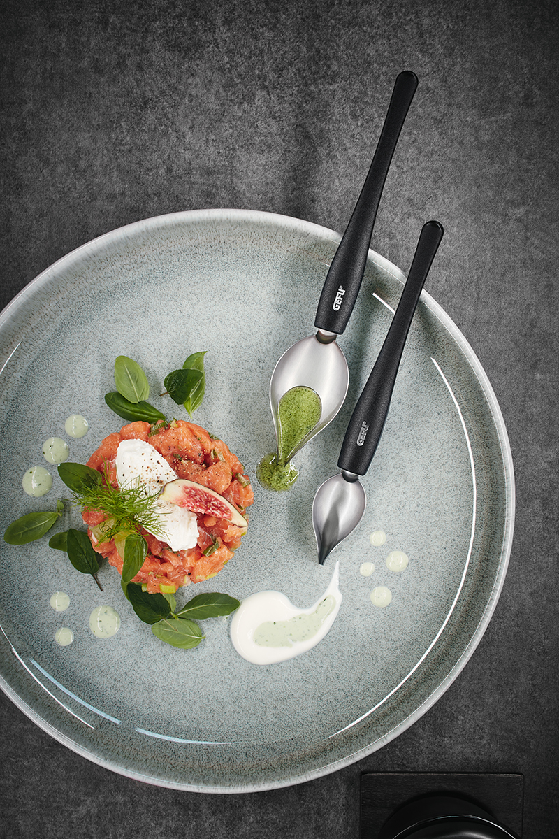 Elegantes Anrichten von Gourmetgerichten mit hochwertigem Besteck Ein stilvoll angerichteter Teller mit frischen Zutaten und Besteck zum Verfeinern von Saucen.