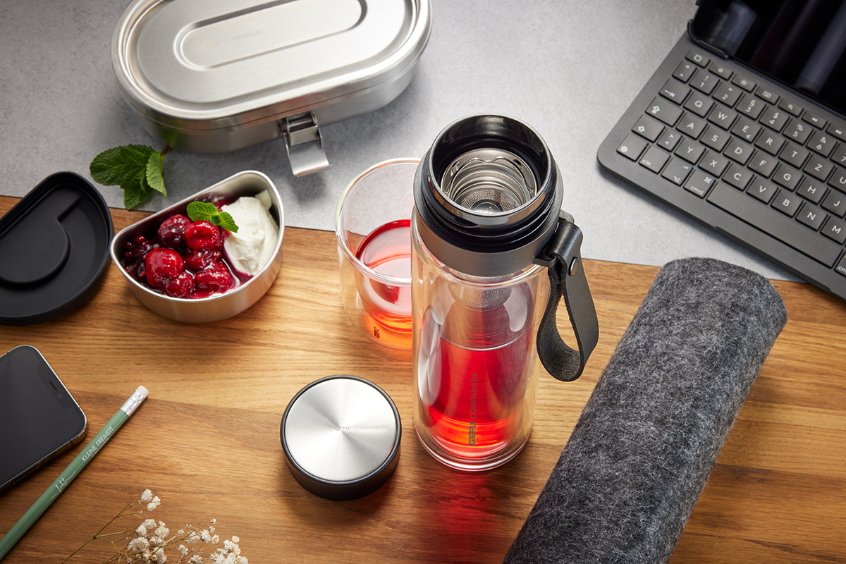 Stilvolles Büroset mit Thermosflasche und Snackbox Moderne Büroeinrichtung mit Thermosflasche, Snackbox mit Beeren und Joghurt, Laptop und Zubehör auf einem Schreibtisch
