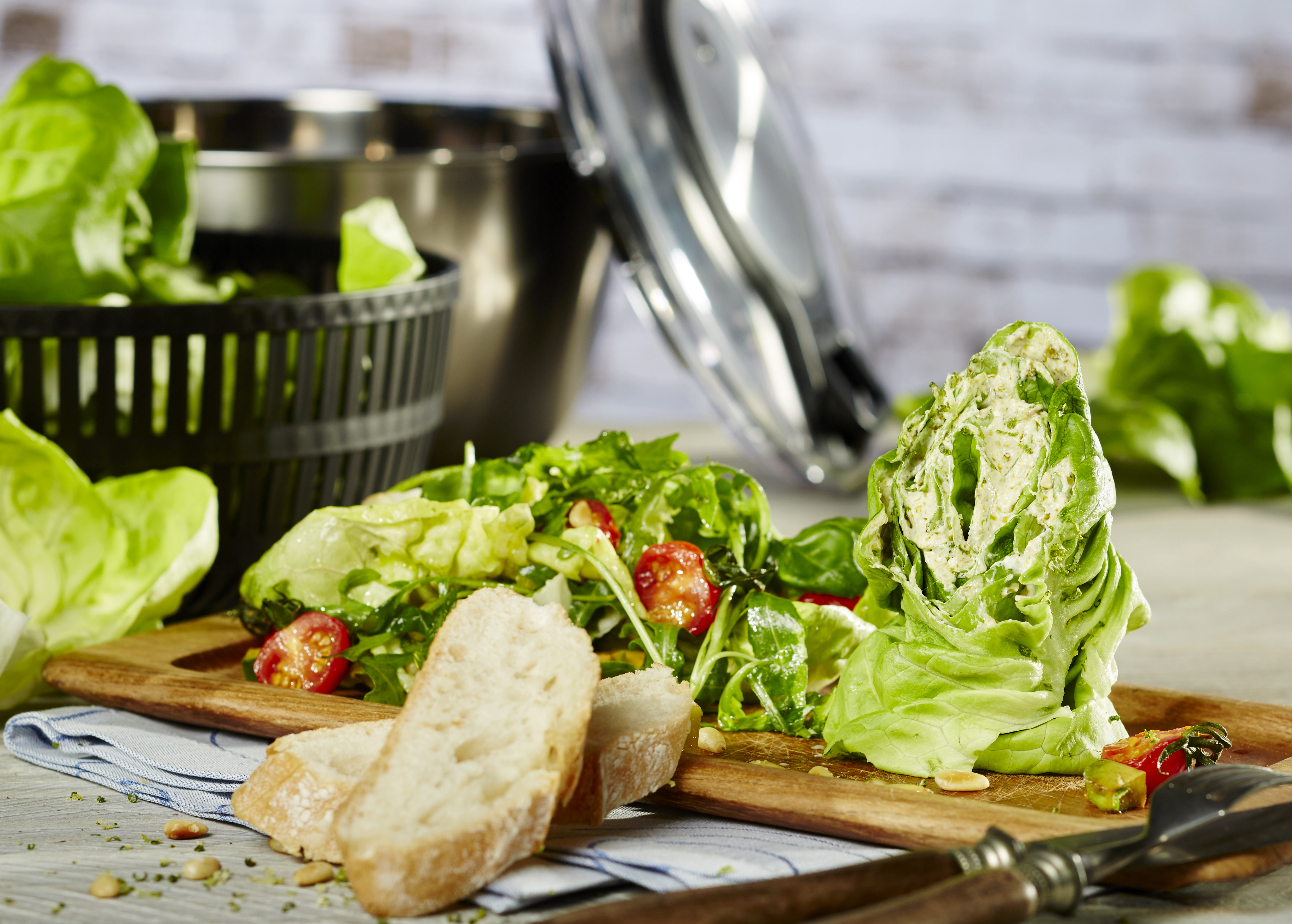 Gefüllte Kopfsalatpäckchen auf italienischem Salat Ein frischer grüner Salat mit Tomaten und Brot wird auf einem Holzbrett serviert.