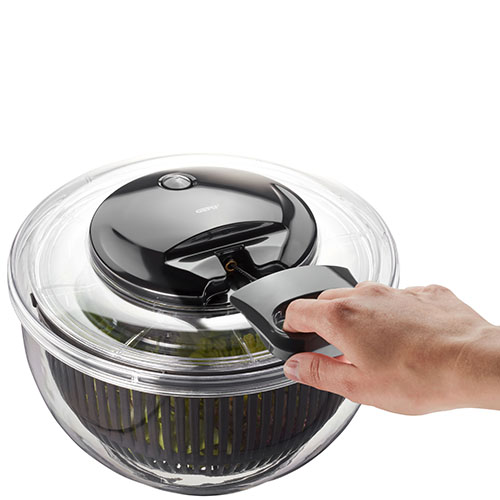 Praktische Salatschleuder mit Kurbelmechanismus Hand bedient eine transparente Salatschleuder mit Kurbel, gefüllt mit grünem Salat