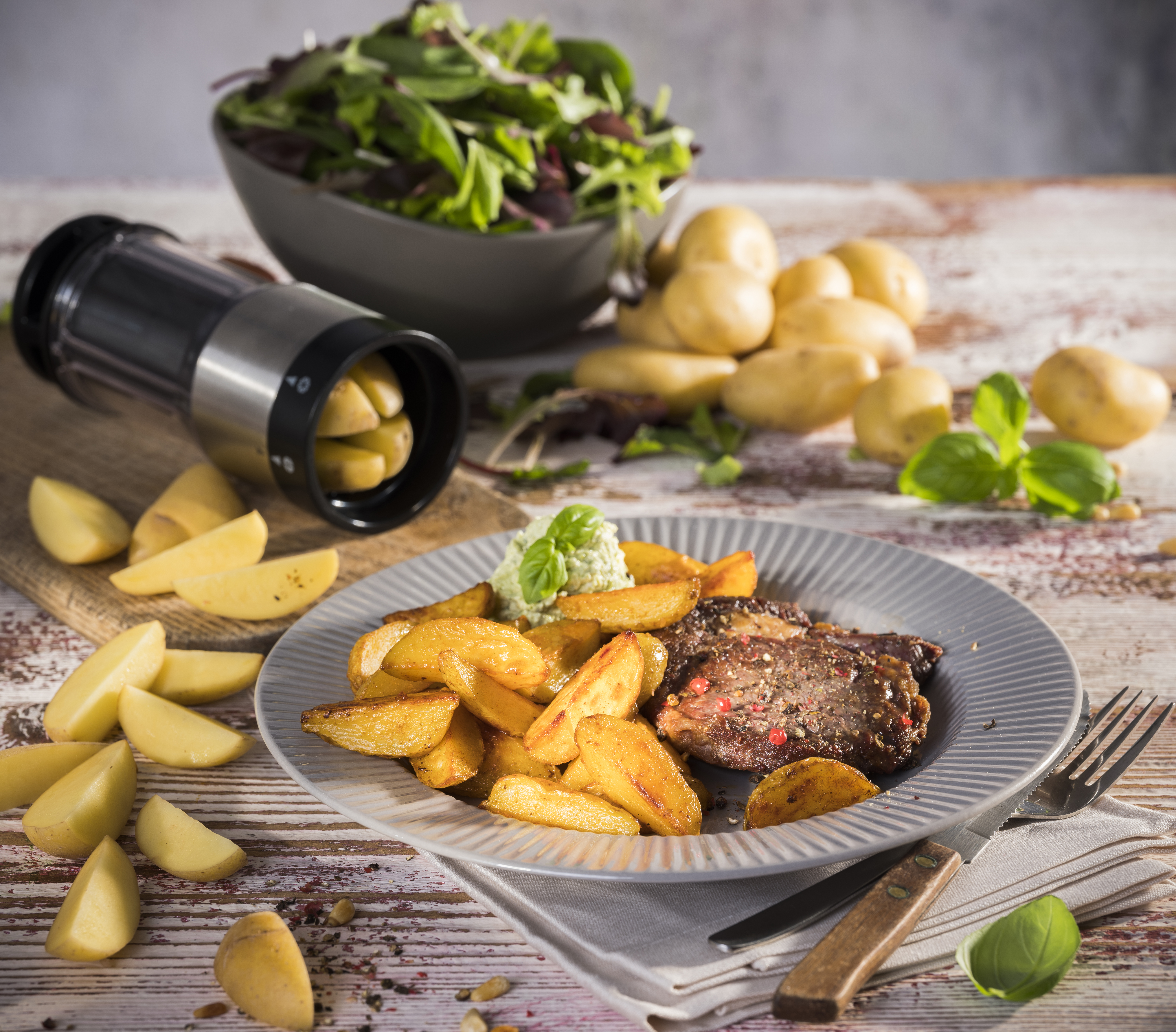 Knusprige Mini-Wedges mit Entrecôte-Steaks und Basilikumdip Eine Mahlzeit mit saftigem Steak, goldenen Kartoffelecken und frischem Blattsalat, dekoriert mit Kräutern und serviert auf einem rustikalen Tisch.