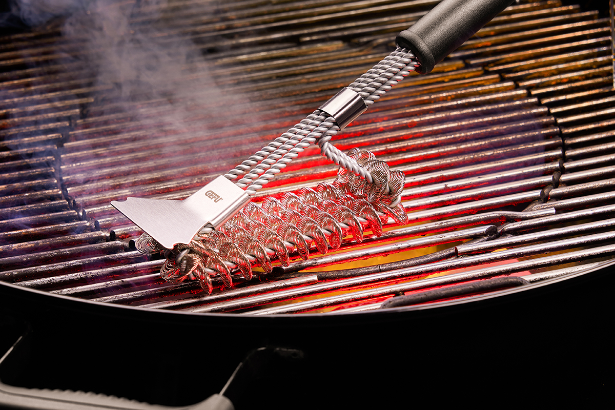 Robuste Grillbürste aus Edelstahlreiniger im Einsatz auf heißem Grillrost Nahaufnahme einer Edelstahl-Grillbürste, die über einen glühenden Grillrost gezogen wird, um diesen zu reinigen