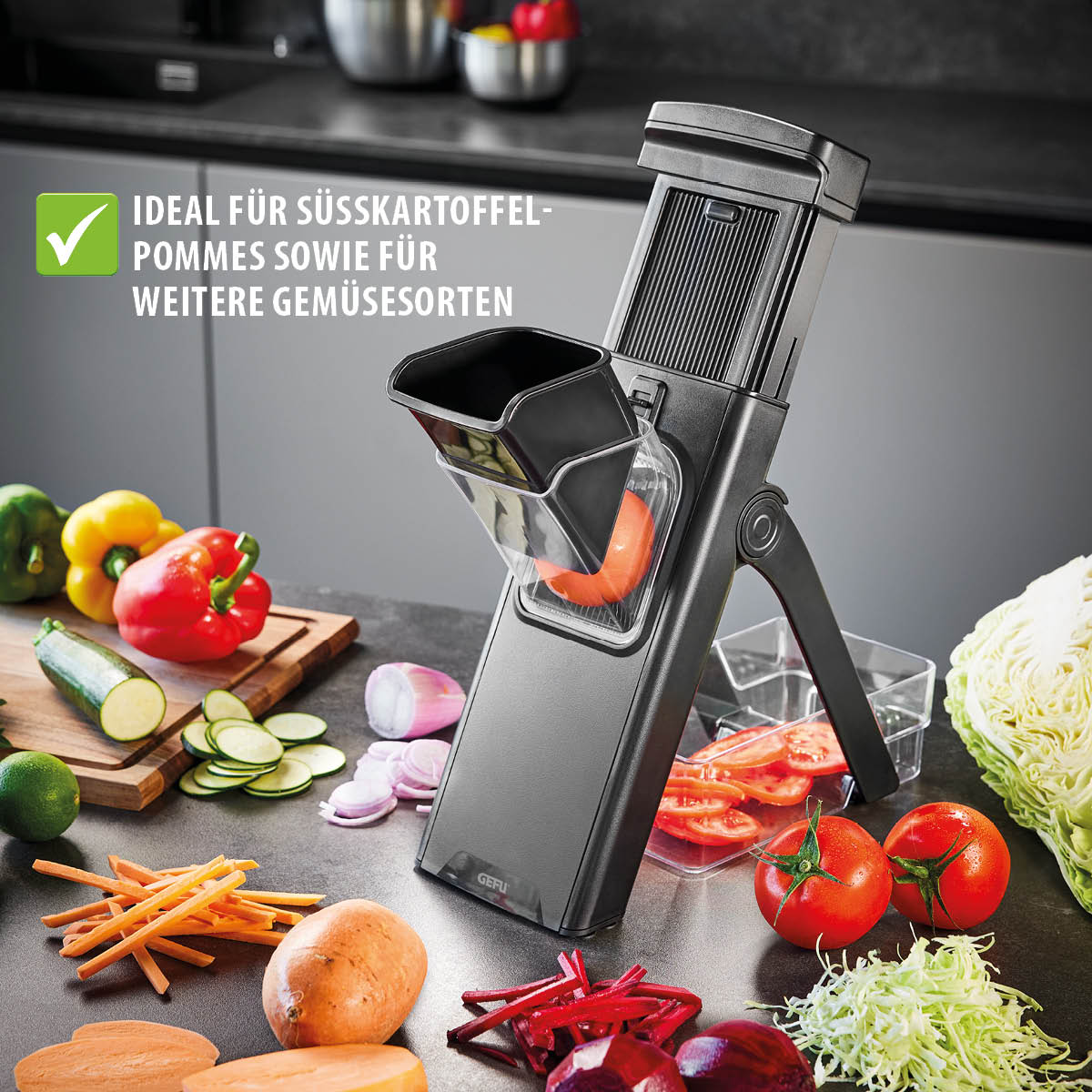 Ein Gemüseschneider auf einer Küchenarbeitsplatte, umgeben von geschnittenem Gemüse wie Süßkartoffeln, Tomaten, Zucchini und Paprika, mit dem Text 'Ideal für Süßkartoffel-Pommes sowie für weitere Gemüsesorten' im Hintergrund.