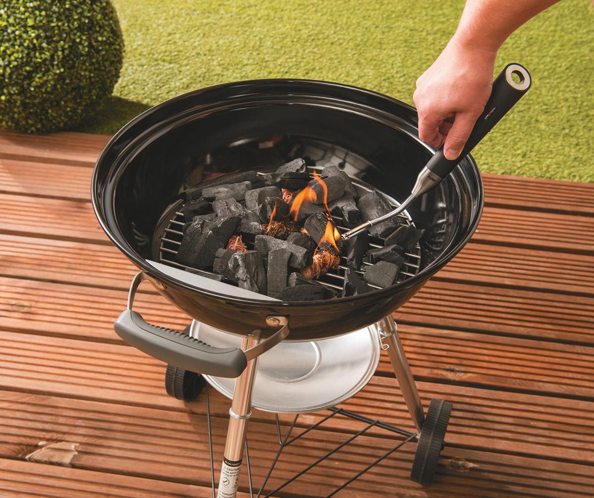 Hand entzündet Kohlegrill auf Holzterrasse Hand entzündet Kohlegrill mit Anzündhilfe auf einer Holzterrasse im Garten
