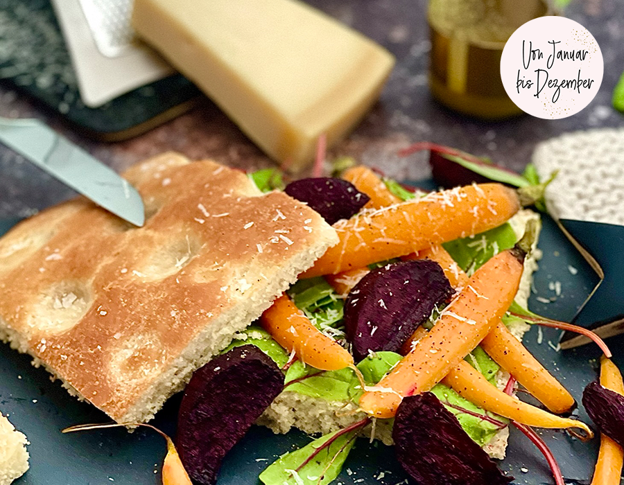 Salad Sandwich  Nahaufnahme eines belegten Focaccia-Sandwiches mit frischen Karotten, Roter Bete und Salat, dekoriert mit Käse.
