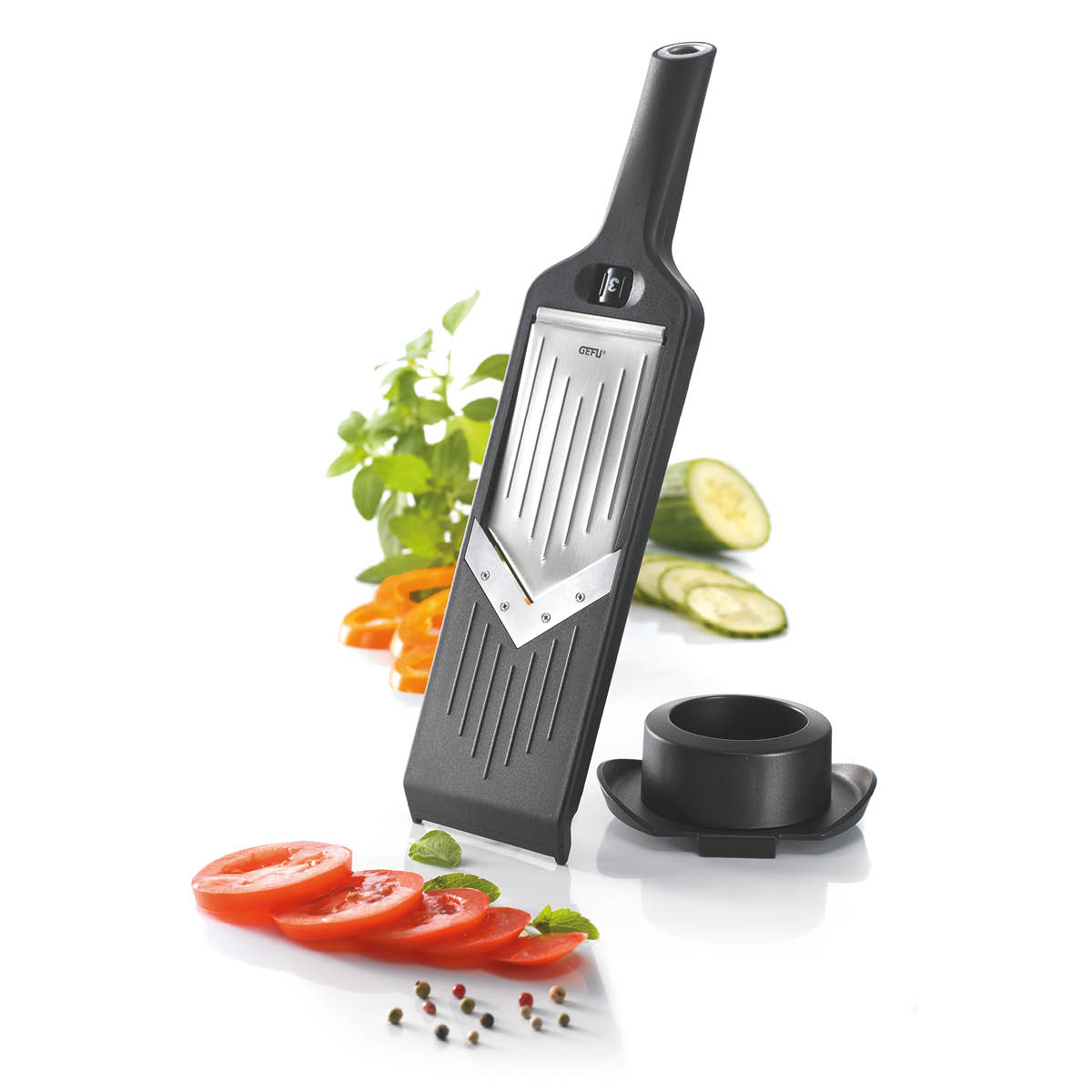Hochwertige Küchenmandoline für gleichmäßige Gemüsescheiben Küchenmandoline mit geschnittenen Tomaten, Gurken und Paprika auf weißem Hintergrund