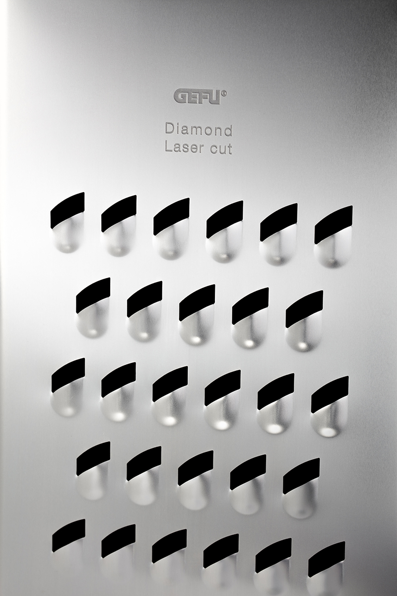 Detail einer hochwertigen Küchenreibe mit Diamantschliff Nahaufnahme der Oberfläche einer Edelstahl-Küchenreibe mit lasergeschnittenen Öffnungen