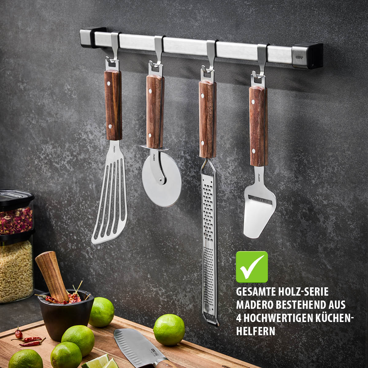 Ein Set aus vier Küchenwerkzeugen aus der Madero-Serie, bestehend aus einem Pfannenwender, Pizzaschneider, Reibe und Käsehobel, an einer Hakenleiste hängend.