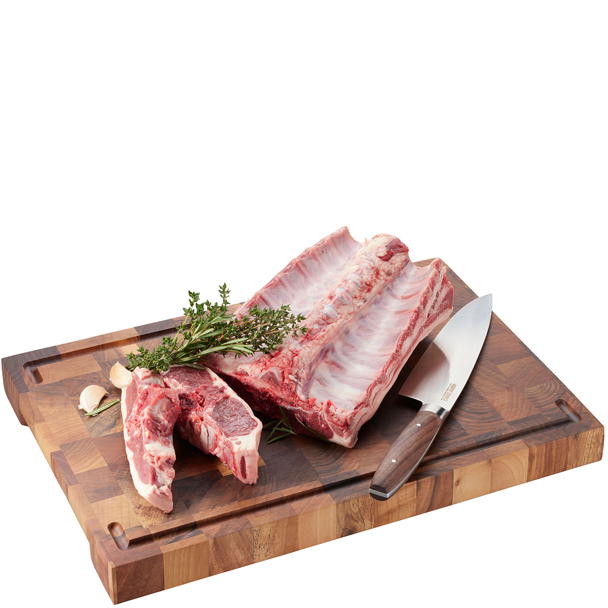 Frische Lammrippchen auf Holzbrett mit Kräutern und Messer Rohes Lammfleisch auf einem Schneidebrett, dekoriert mit Kräutern und einem Fleischmesser
