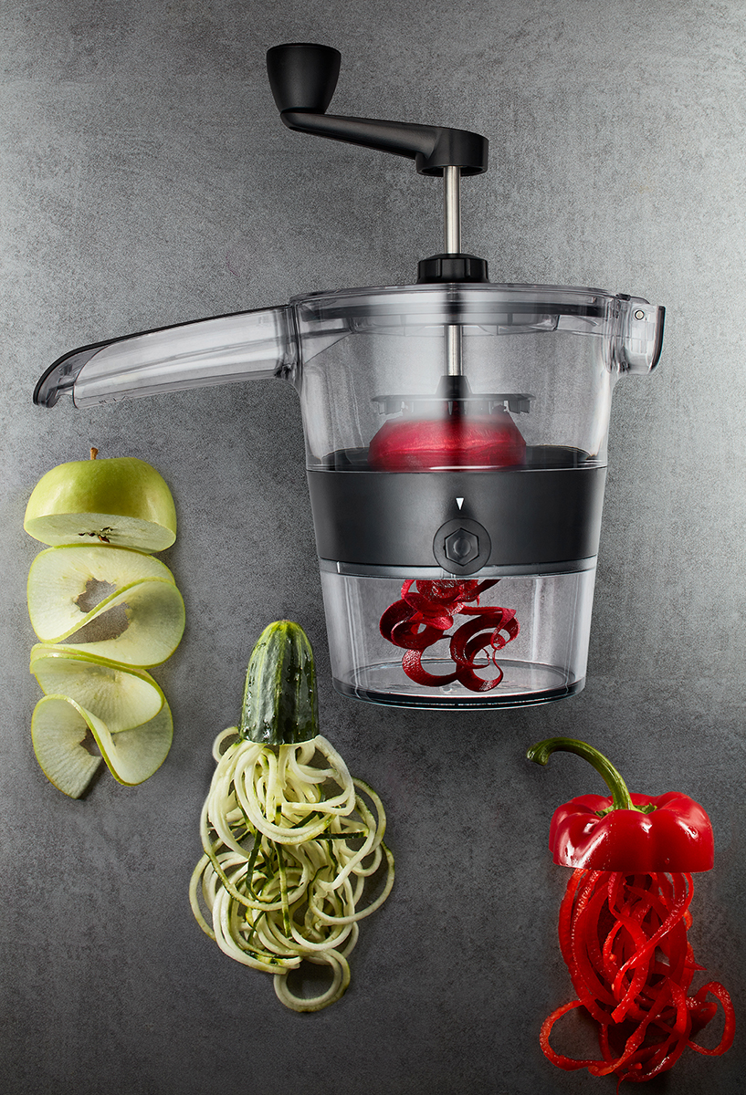 Manuelle Gemüsespiralschneider mit geschnittenem Apfel, Zucchini und Paprika Manueller Spiralschneider, der Apfel, Zucchini und Paprika in Spiralen schneidet