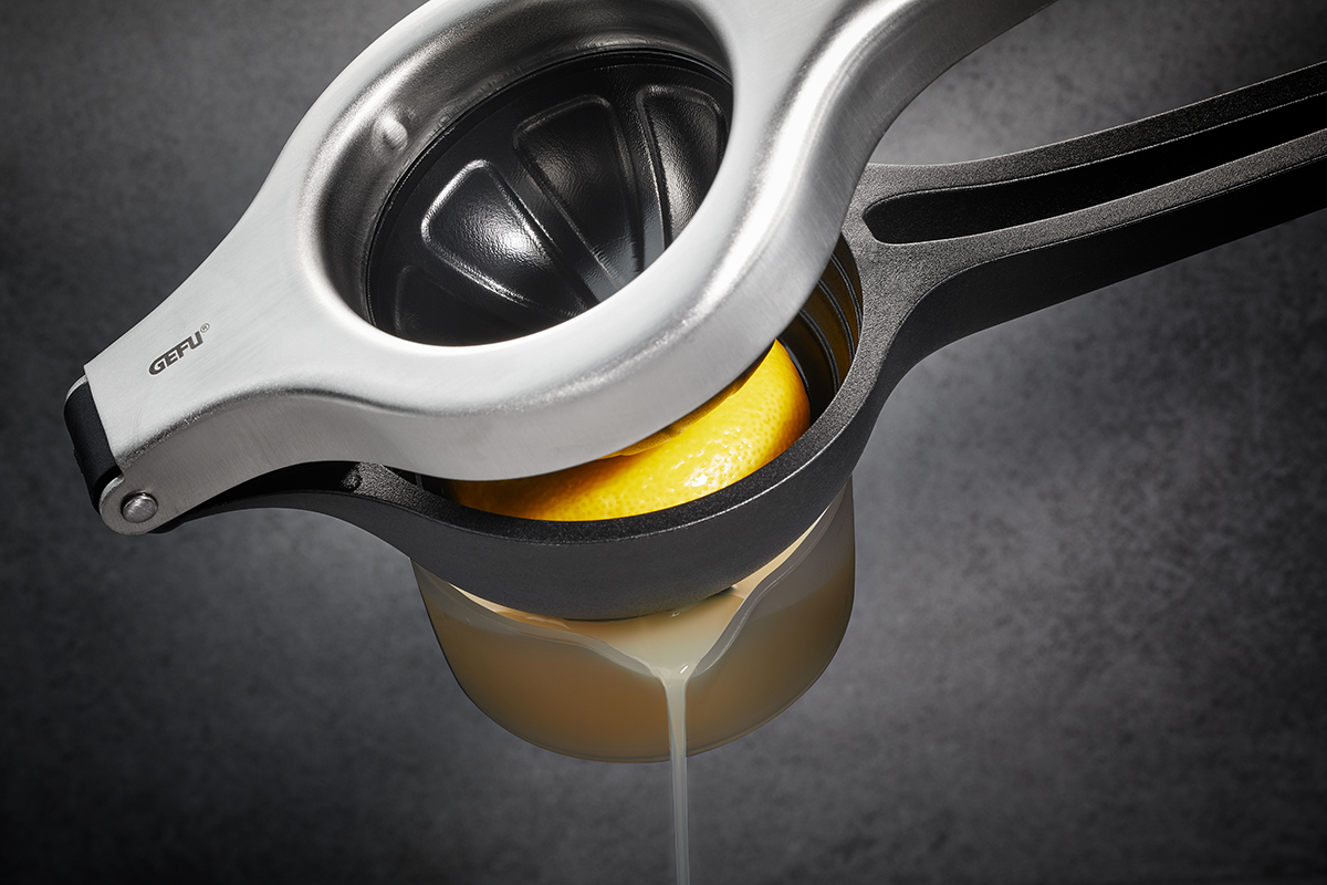 Hochwertiger Zitronenpresse aus Edelstahl in Aktion Eine Zitronenpresse aus Edelstahl presst eine halbe Zitrone aus, um frischen Saft zu gewinnen.