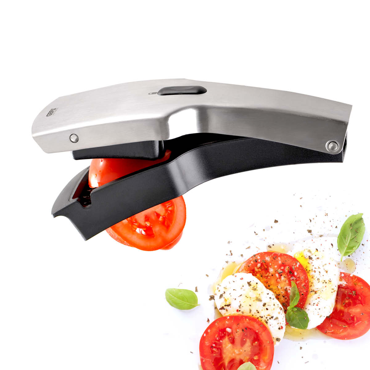 Tomatenschneider aus Edelstahl, der eine Tomate in gleichmäßige Scheiben schneidet, neben einem Caprese-Salat