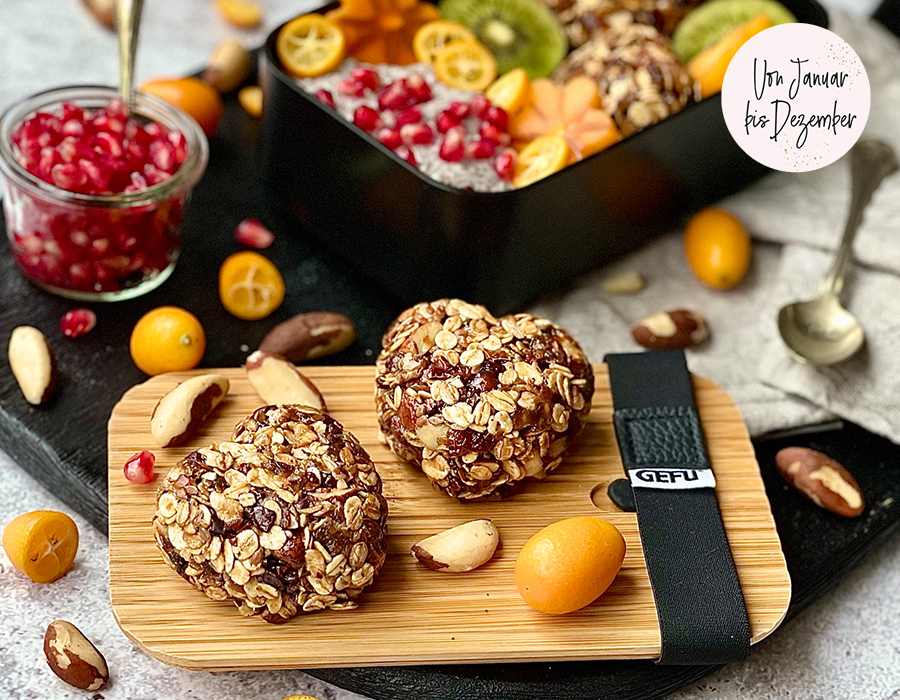 Müsliherzen Herzförmige Müsliriegel mit Nüssen und Früchten auf einem Holzbrett, umgeben von Granatapfelkernen, Kumquats und Paranüssen