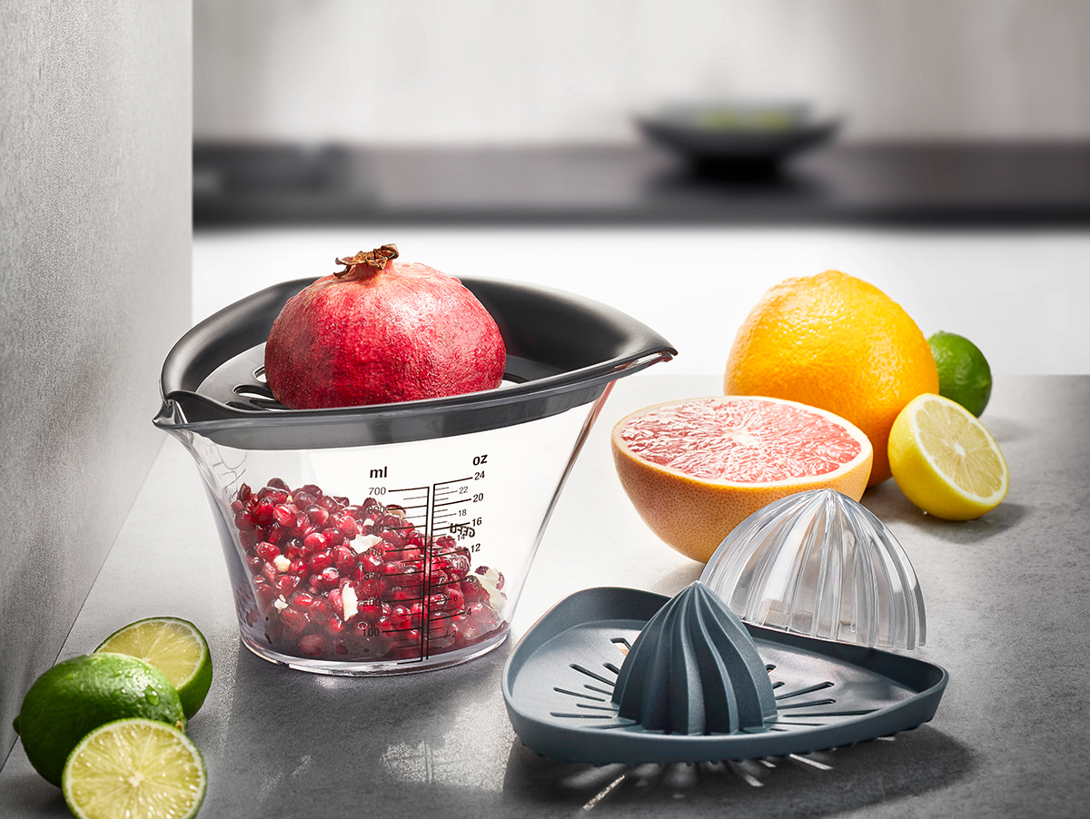 Mehrzweck-Saftpresse mit Granatapfel, Grapefruit, Zitrone und Limette auf einer Küchenarbeitsplatte