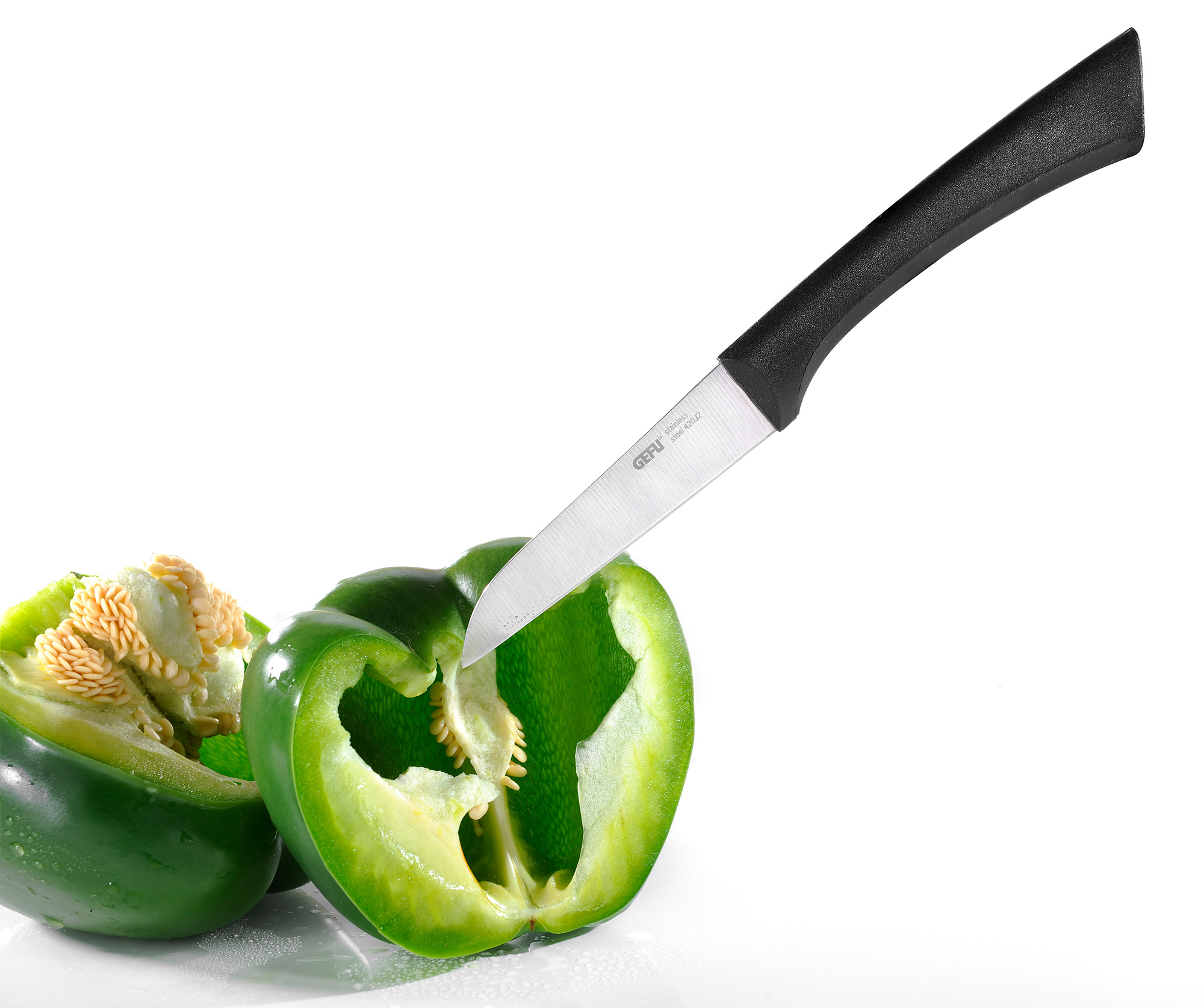 Küchenmesser schneidet grüne Paprika Ein Küchenmesser mit schwarzem Griff schneidet eine frische grüne Paprika auf weißem Hintergrund.