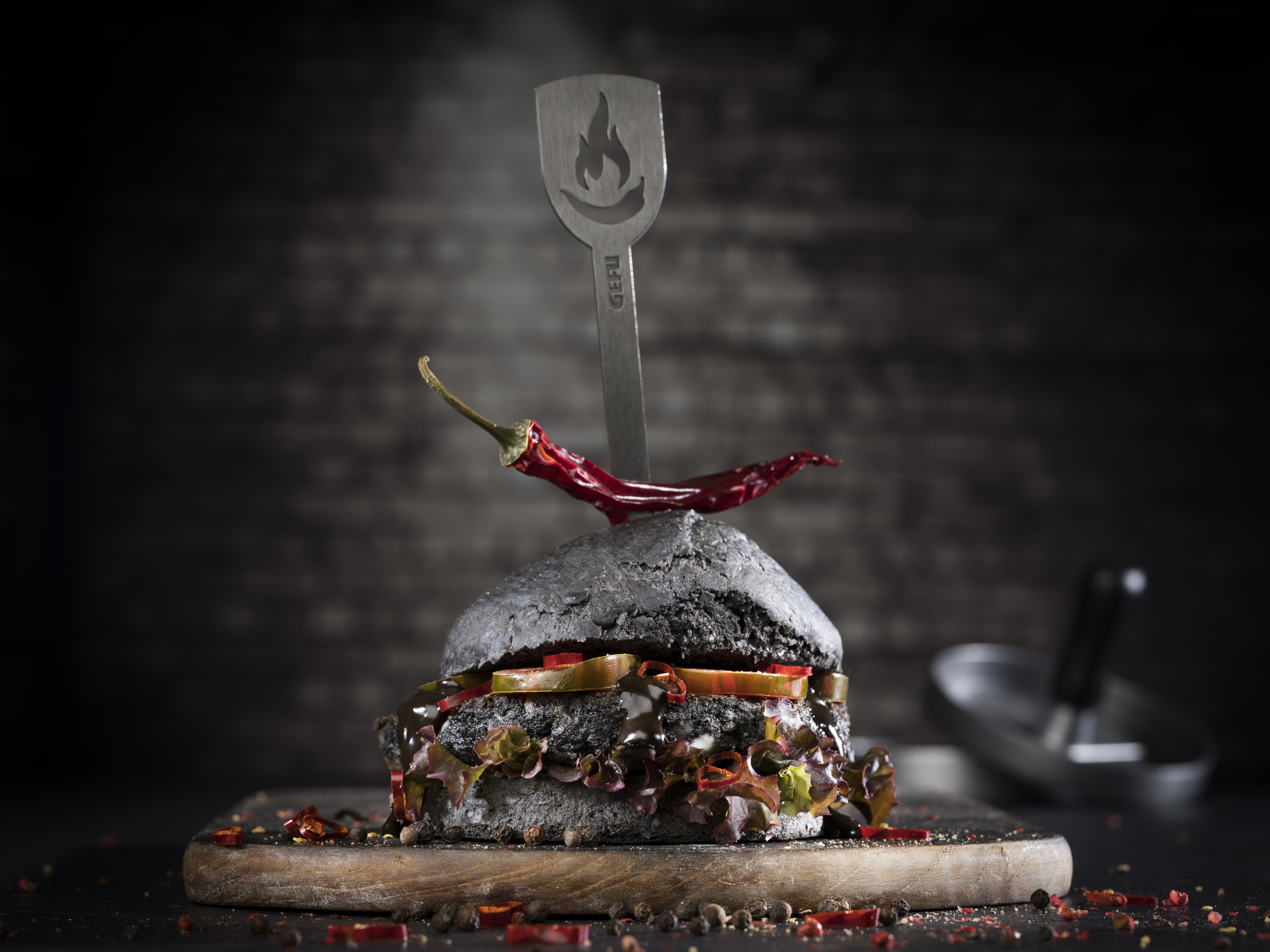 Schwarzer Burger mit Fischfrikadelle und schwarzem Knoblauch-Chili-Dipp