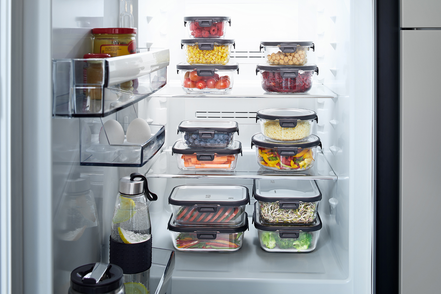 Kühlschrank mit verschiedenen frischhaltenden Lebensmitteldosen Ein geöffneter Kühlschrank, der verschiedene Lebensmittel in transparenten Frischhaltedosen zeigt
