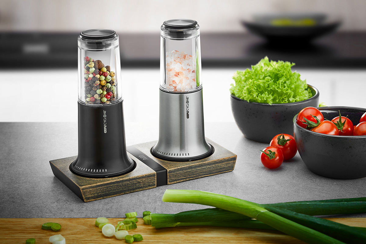 Elektrische Gewürzmühlen mit Holzständer in moderner Küche Zwei elektrische Gewürzmühlen auf einem Holzständer, gefüllt mit Pfefferkörnern und Himalayasalz, in einer modernen Küchenszene mit frischen Zutaten im Hintergrund