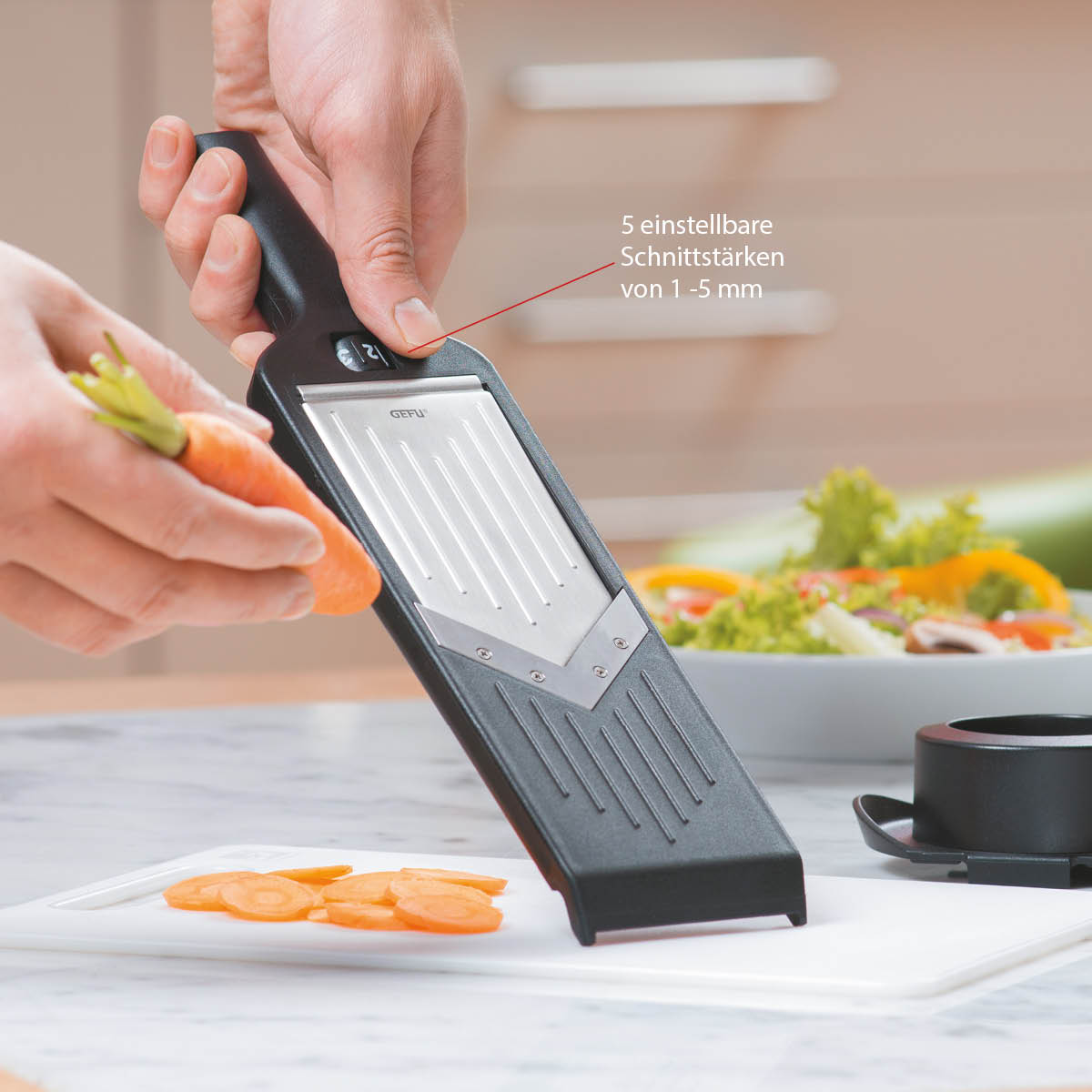 Verstellbarer Gemüsehobel mit 5 Schnittstärken für präzises Schneiden Hand hält einen Gemüsehobel, der Möhren in Scheiben schneidet. Im Hintergrund Salat auf einem Küchentisch.