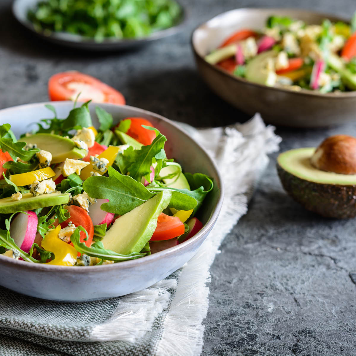 Frischer Avocado-Rucola-Salat mit buntem Gemüse Nahaufnahme eines frischen Salats mit Avocado, Rucola und verschiedenen Gemüsesorten in einer Schüssel