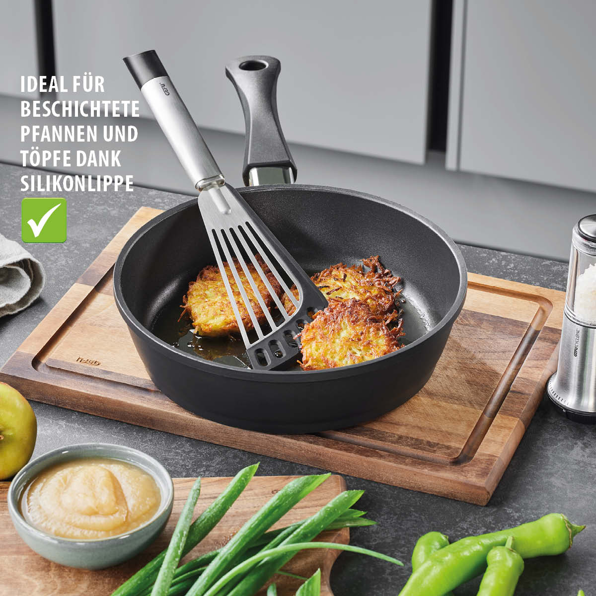 Pfannenwender mit Silikonlippe – ideal für beschichtete Pfannen und Töpfe Pfannenwender in einer Pfanne mit Rösti, umgeben von Frühlingszwiebeln und Apfelmus auf einem Schneidebrett