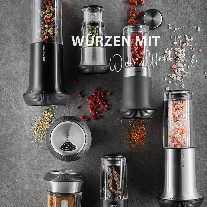 Verschiedene Gewürzmühlen mit bunten Pfefferkörnern und Salz auf grauem Hintergrund