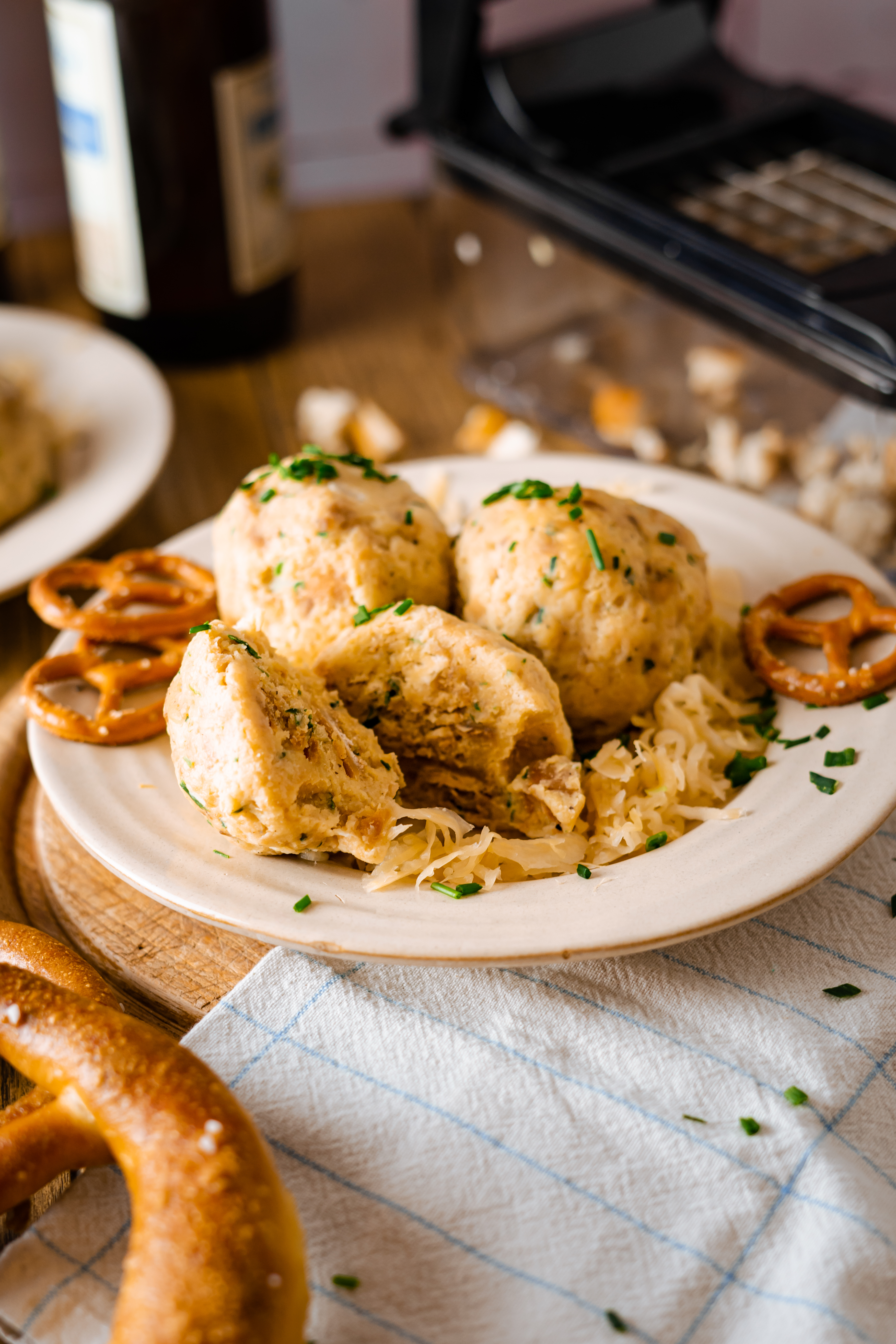 Laugenknödel zum Oktoberfest Eine Portion Semmelknödel mit Sauerkraut und Brezen auf einem Teller, dekoriert mit frischen Kräutern, auf einem Holztisch serviert