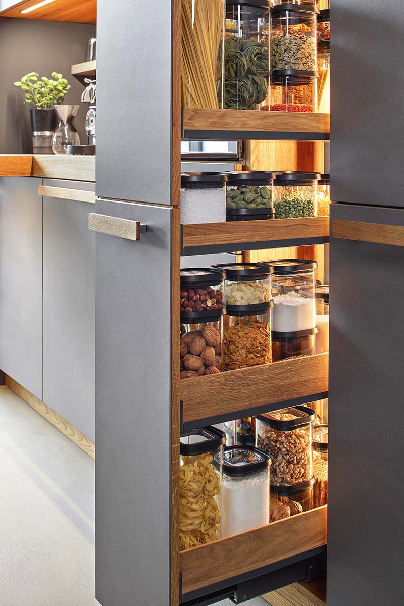 Moderne Küchenspeisekammer mit Vorratsbehältern Ausziehbares Regal in einer Küche, gefüllt mit Vorratsbehältern für Nudeln, Nüsse, und andere Vorräte
