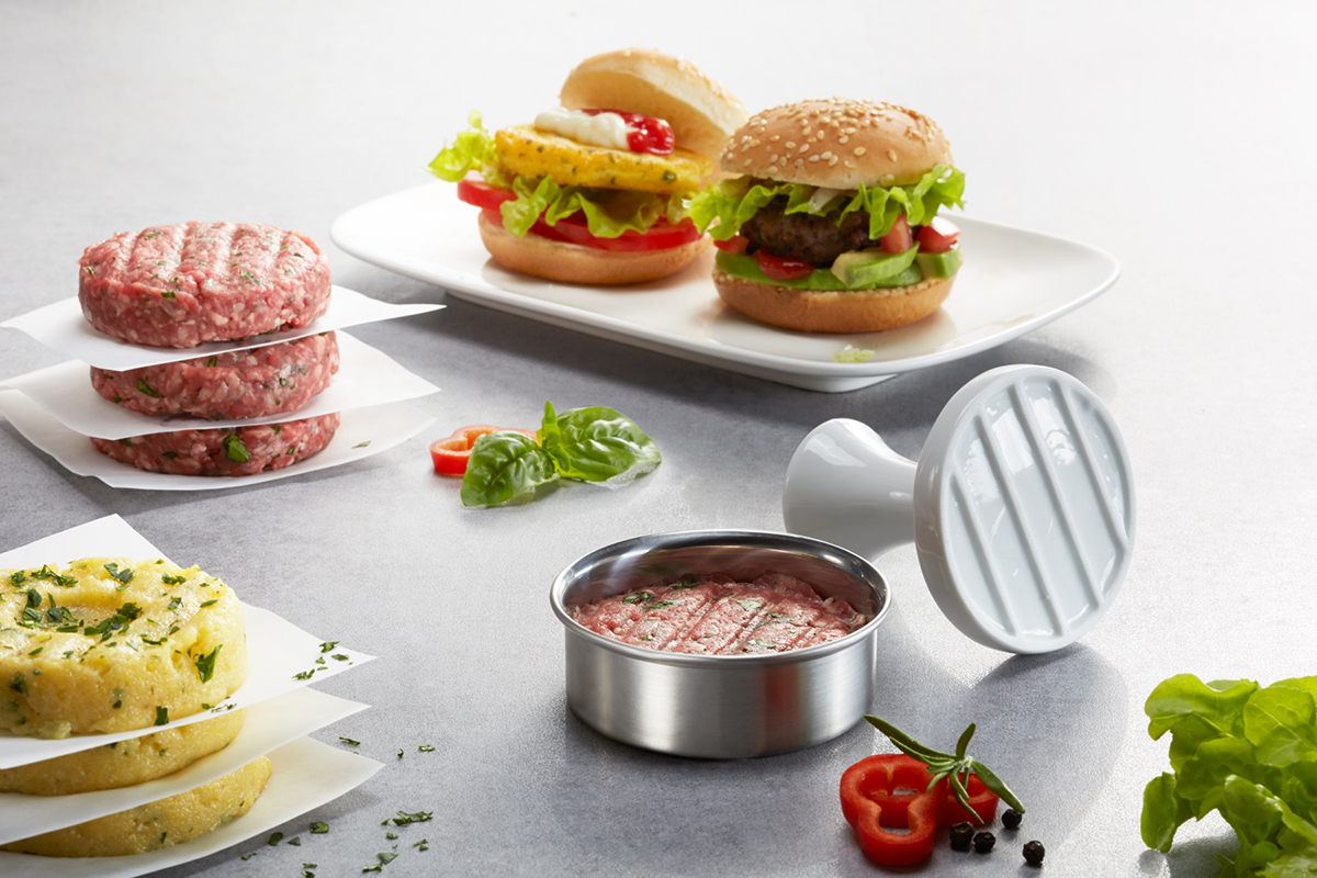 Burgerpresse mit frischem Hackfleisch und geformten Patties Nahaufnahme einer Burgerpresse mit Hackfleischpatties und fertigen Burgern auf einem Tisch
