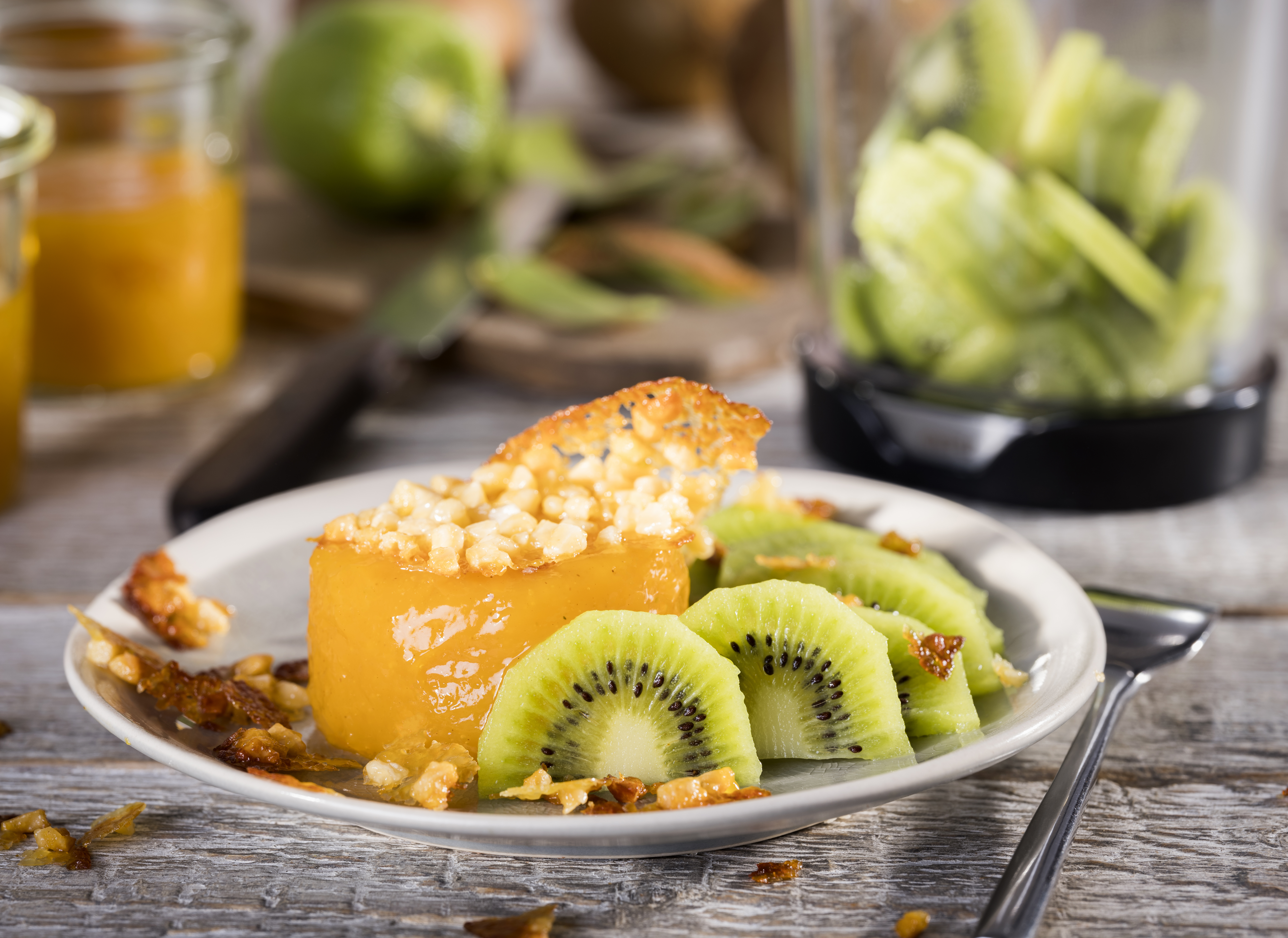 Kiwi with passion fruit pudding and brittle Ein Teller mit frischen Kiwi-Scheiben und einem süßen Dessert, garniert mit knusprigen Nüssen.