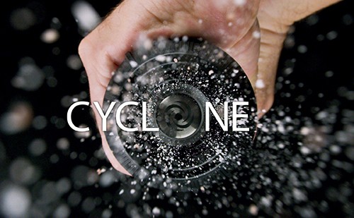 Kreatives Foto einer Hand, die einen Wirbel erzeugt Nahaufnahme einer Hand, die einen wirbelnden Effekt mit Wasser oder Pulver erzeugt, mit dem Wort 'CYCLONE' darüber.