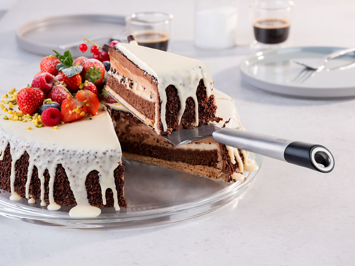 Schokoladentorte mit weißer Glasur und frischen Beeren auf Glasplatte