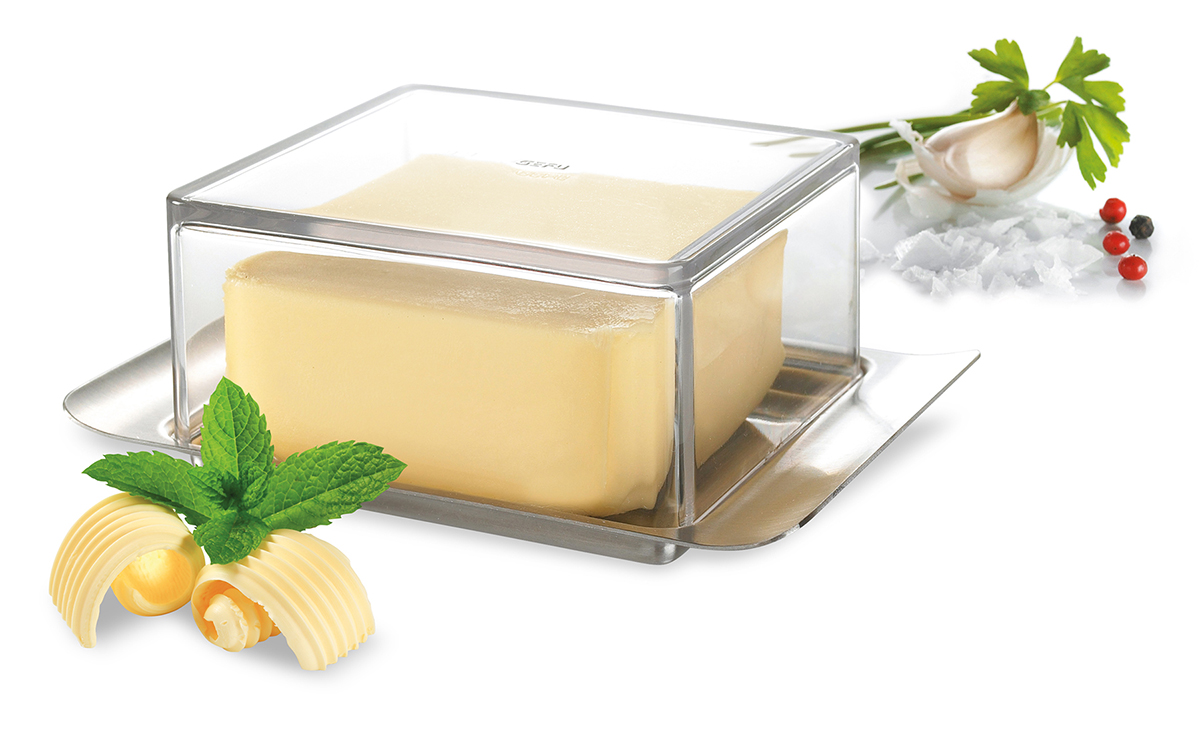 Elegante Butterdose mit Kräutern verziert für eine stilvolle Küche Butter in einer eleganten transparenten Butterdose mit frischen Kräutern, Knoblauch und Gewürzen auf einem Tisch
