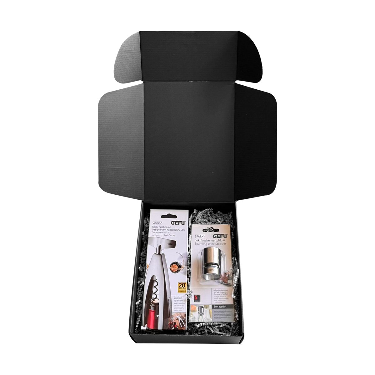 Offene schwarze Geschenkbox mit einem Weinöffner und einem Sektverschluss der Marke GEFU, umgeben von Verpackungsmaterial.