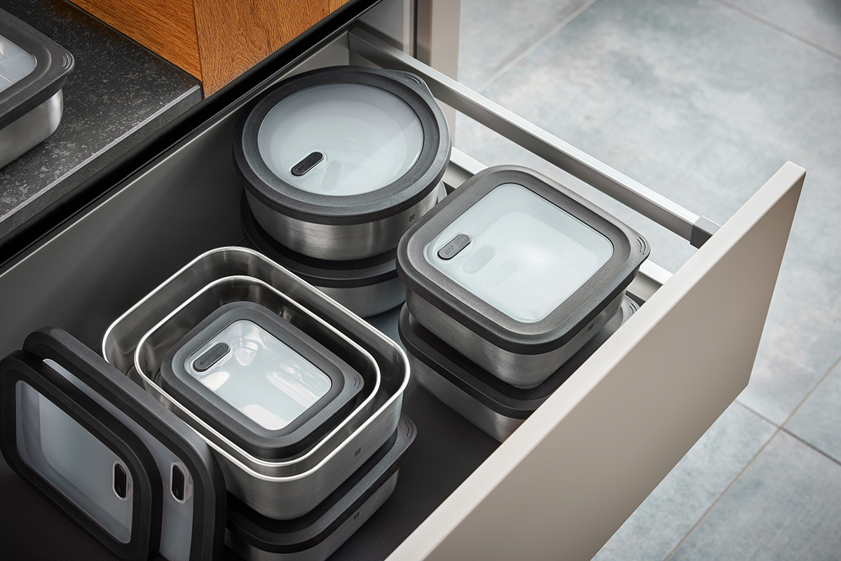 Aufbewahrungsboxen aus Edelstahl mit Deckeln in Küchenschublade Verschiedene stapelbare Edelstahl-Aufbewahrungsdosen mit Kunststoffdeckeln in geöffneter Schublade